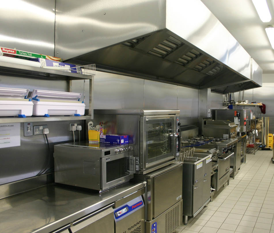 Stainless steel extraction canopy above the range in a commercial kitchen